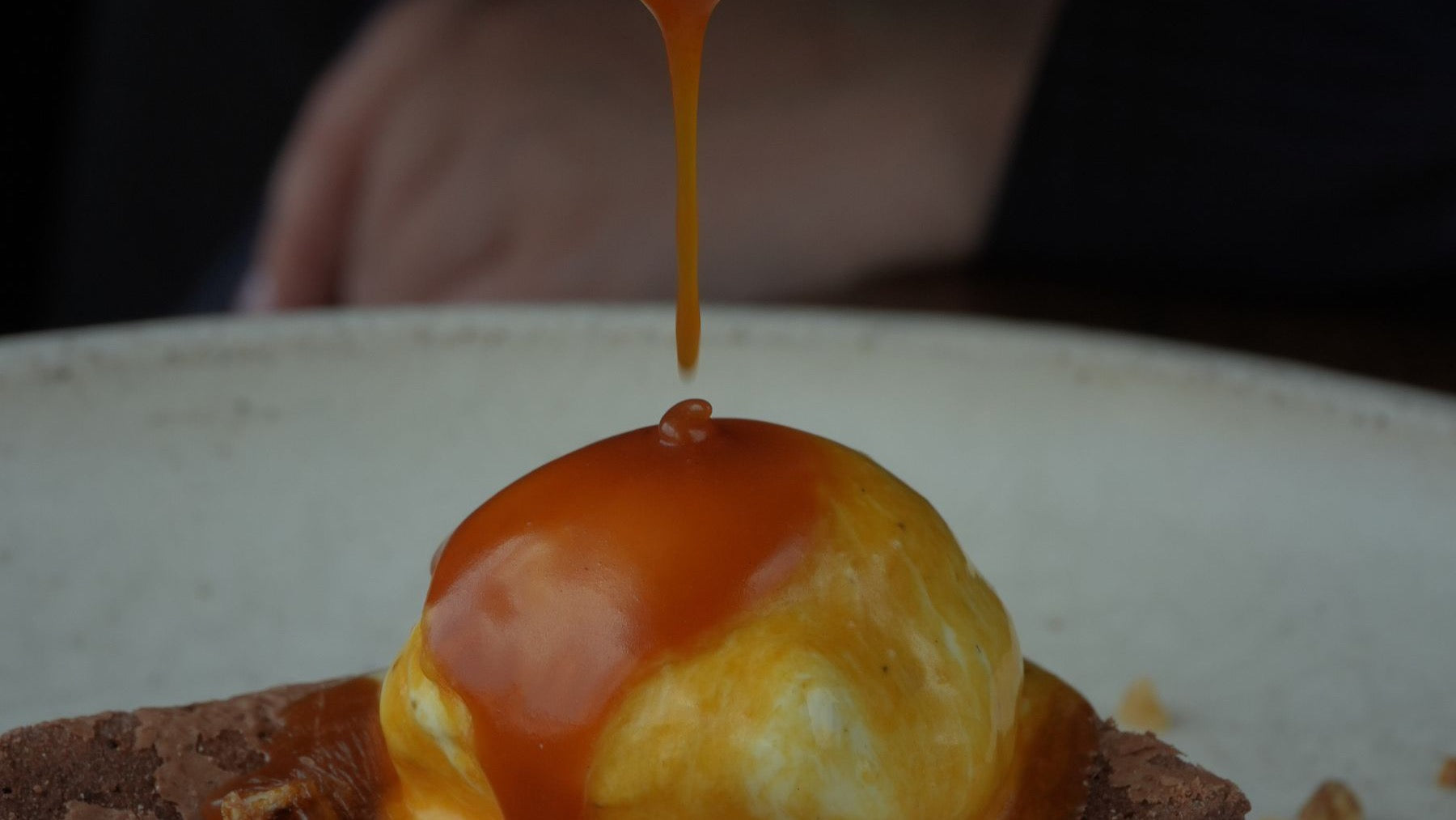 Caramel sauce is poured over a brownie and vanilla ice cream to illustrate dulce de leche dessert ideas.