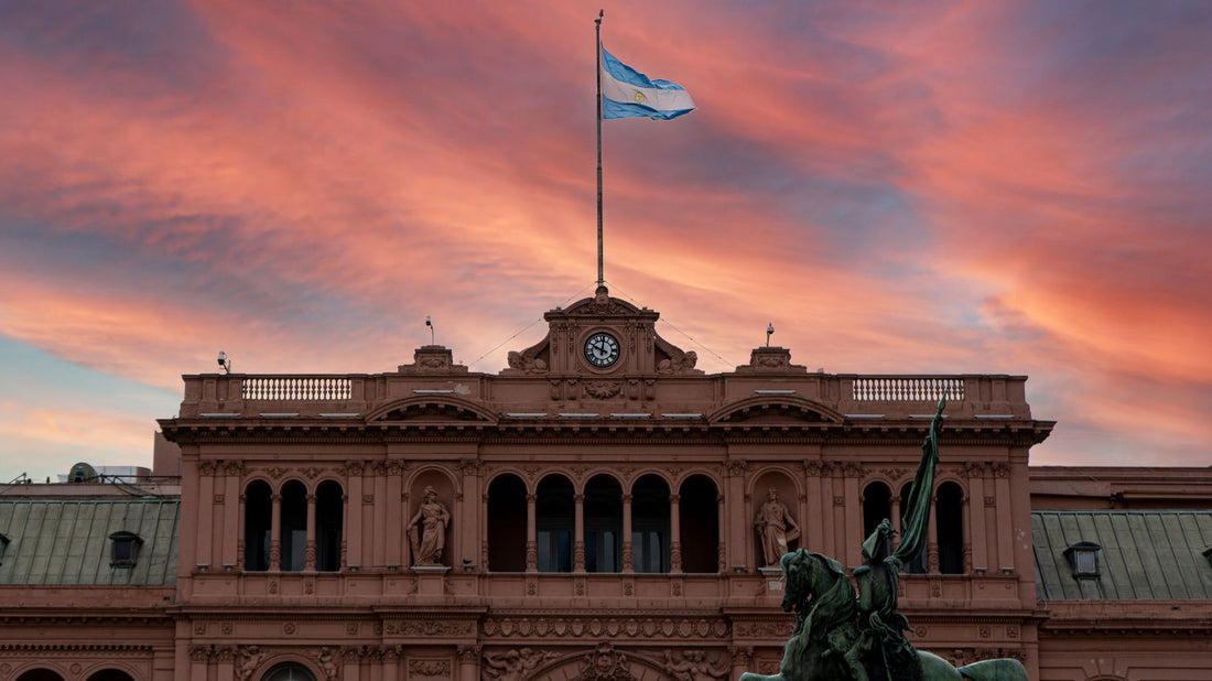 The Argentine flag flies above Casa Rosada beneath a vivid sunset sky in Buenos Aires.