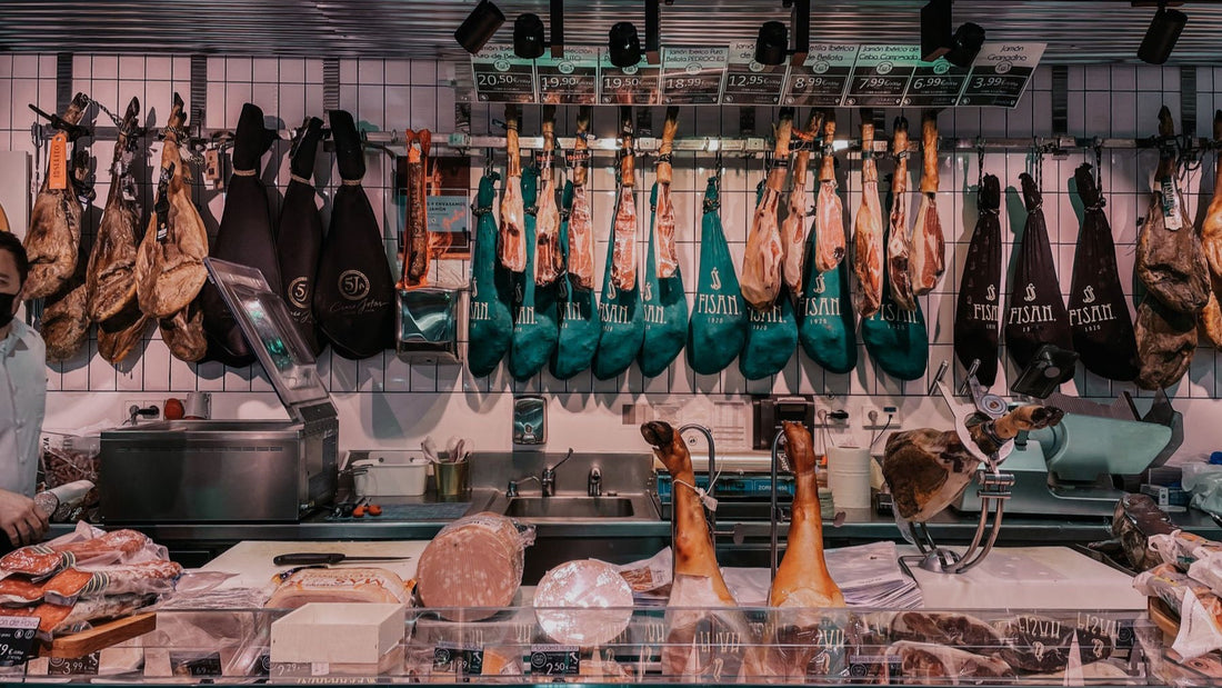 Cured hams, cheeses and deli meats fill the counter of a traditional delicatessen.