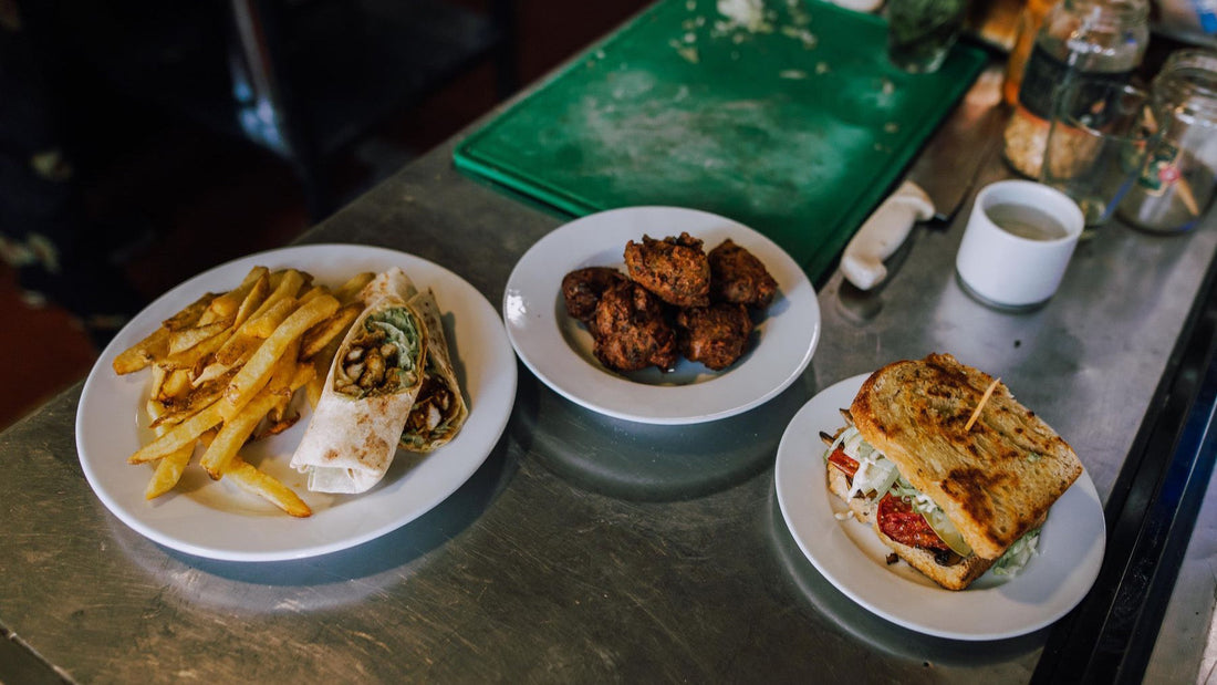 Several plated dishes from an Argentine eatery are arranged across a stainless-steel counter.