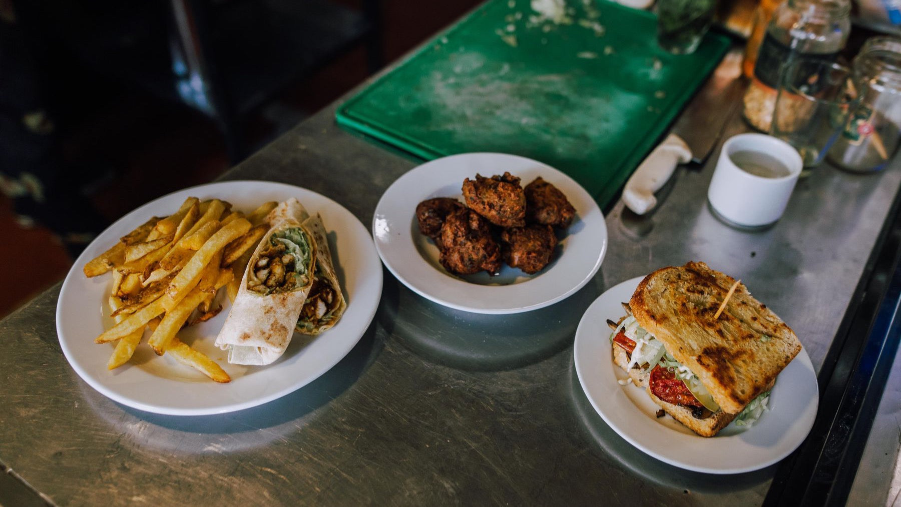 Several plated dishes from an Argentine eatery are arranged across a stainless-steel counter.