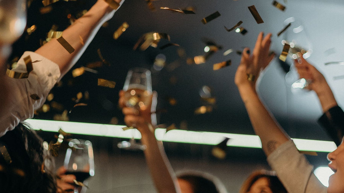 Friends raise sparkling wine beneath falling gold confetti during a New Year's Eve celebration.