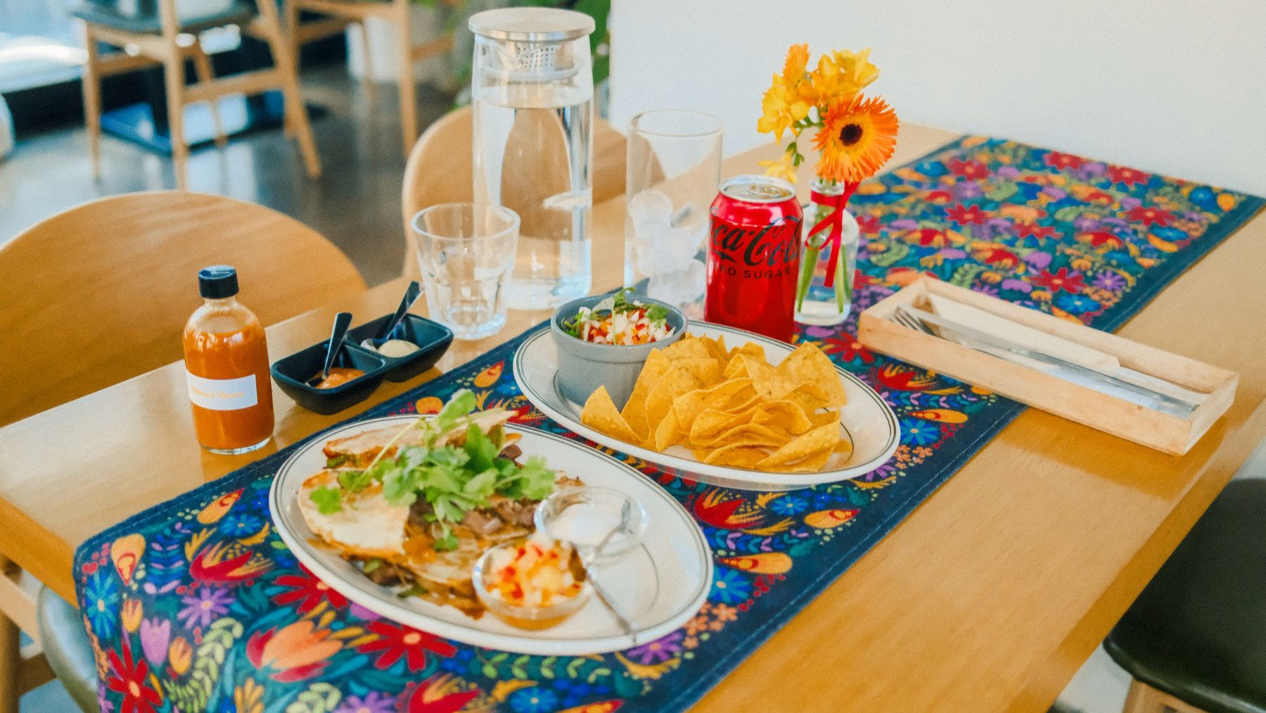 A vibrant Mexican meal is served with tortilla chips, salsa and colourful table textiles.