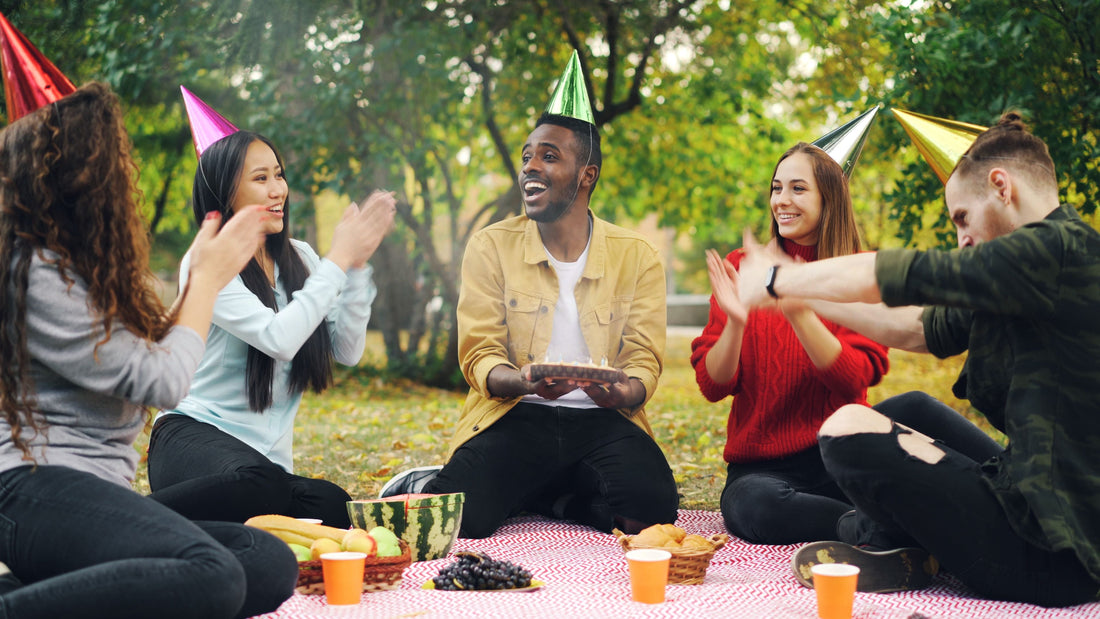 Friends celebrate together at an outdoor summer picnic with snacks.