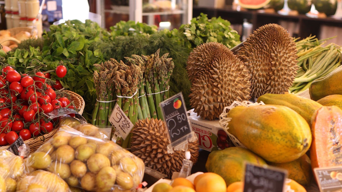 Fresh fruit, vegetables and herbs fill a colourful indoor market stall.
