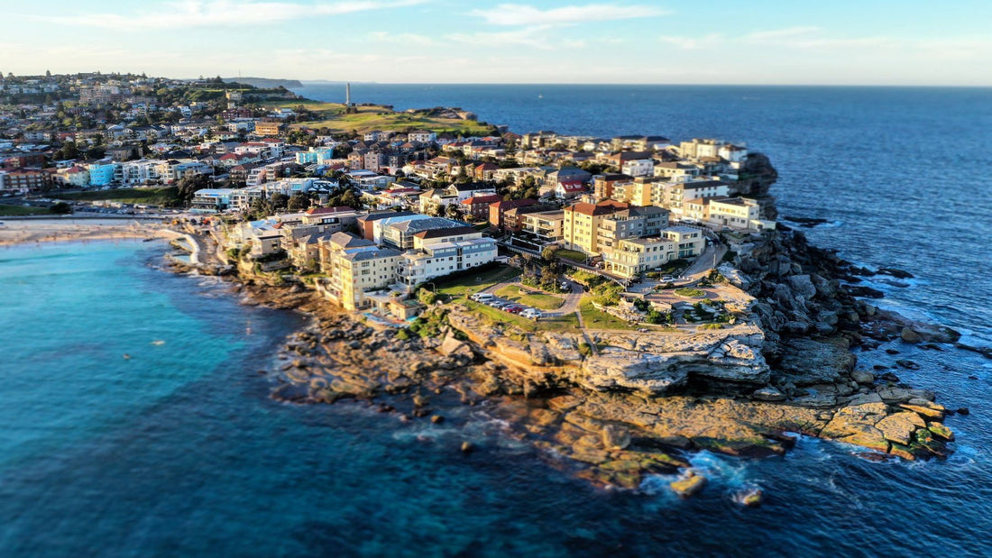 An aerial view looks across North Bondi's coastline, homes and clear blue ocean.