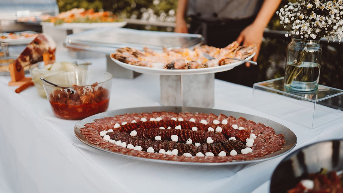 Large platters of appetisers and seafood are arranged across an outdoor catering buffet.
