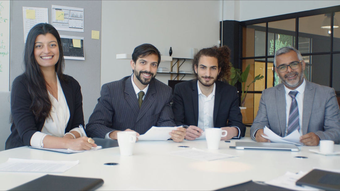 Four business colleagues sit together around a bright conference table in a modern office.