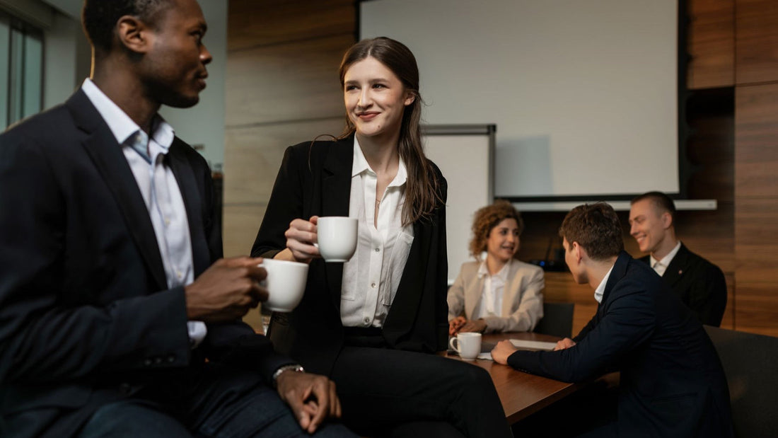 Conference attendees talk over coffee during a break in a professional meeting room.