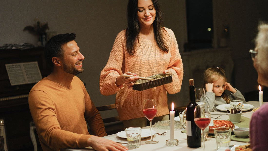 A family gathers around a candlelit dinner table for a relaxed meal at home.