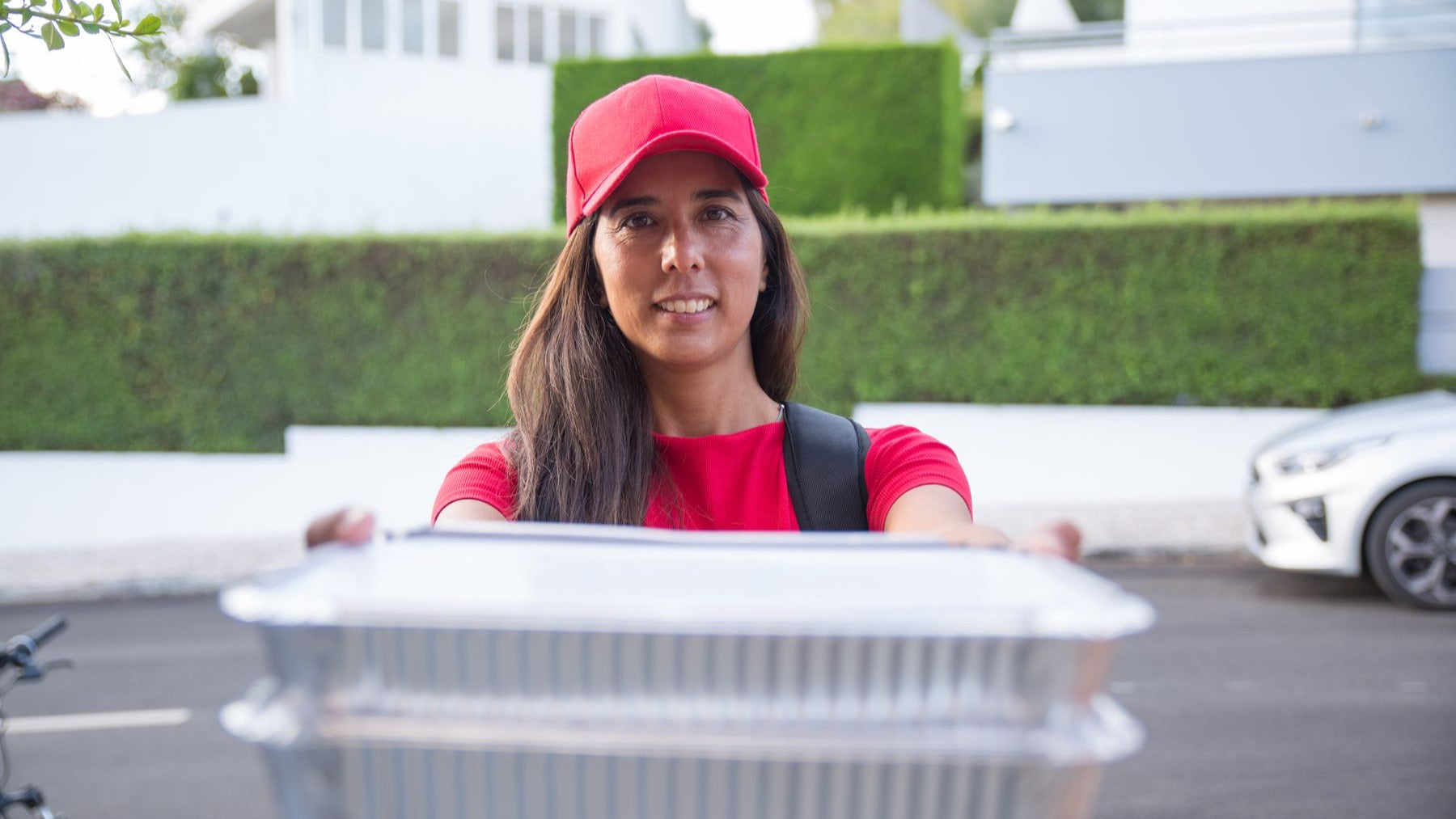 A food courier hands over covered takeaway containers during a home delivery.