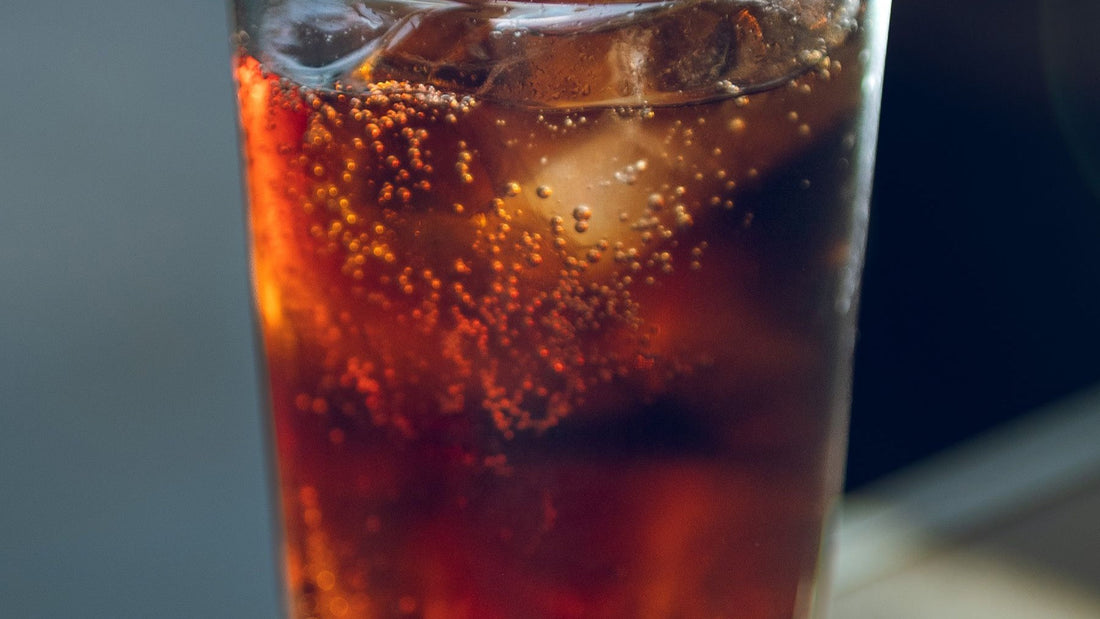 A chilled glass of fernet and cola catches warm light at a Buenos Aires café.
