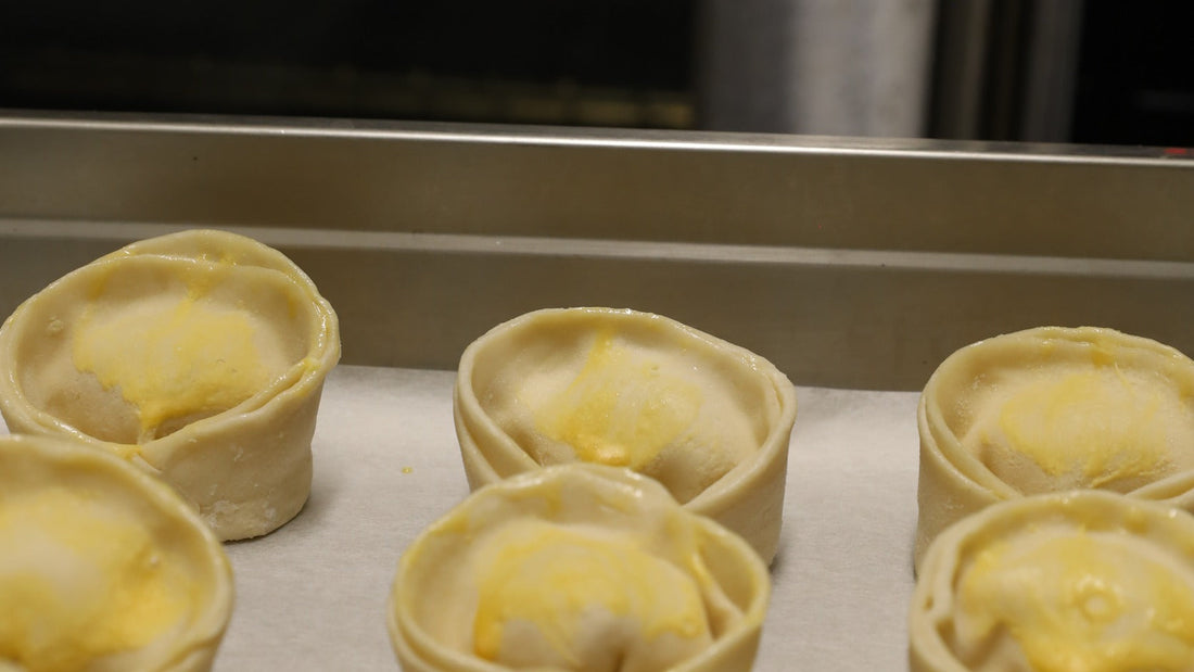 Genuine raw sealed round Argentum empanadas arranged on a kitchen tray.