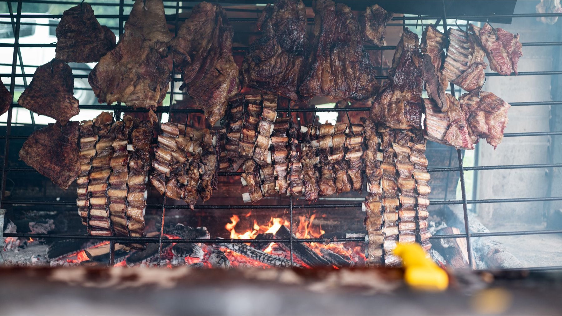Traditional Argentinian asado meats cook over an open wood fire and metal grill.
