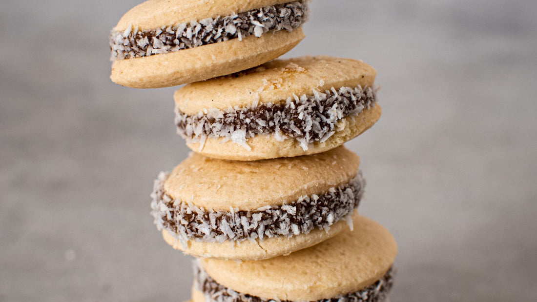 Homemade alfajores filled with dulce de leche and edged with coconut are stacked for serving.