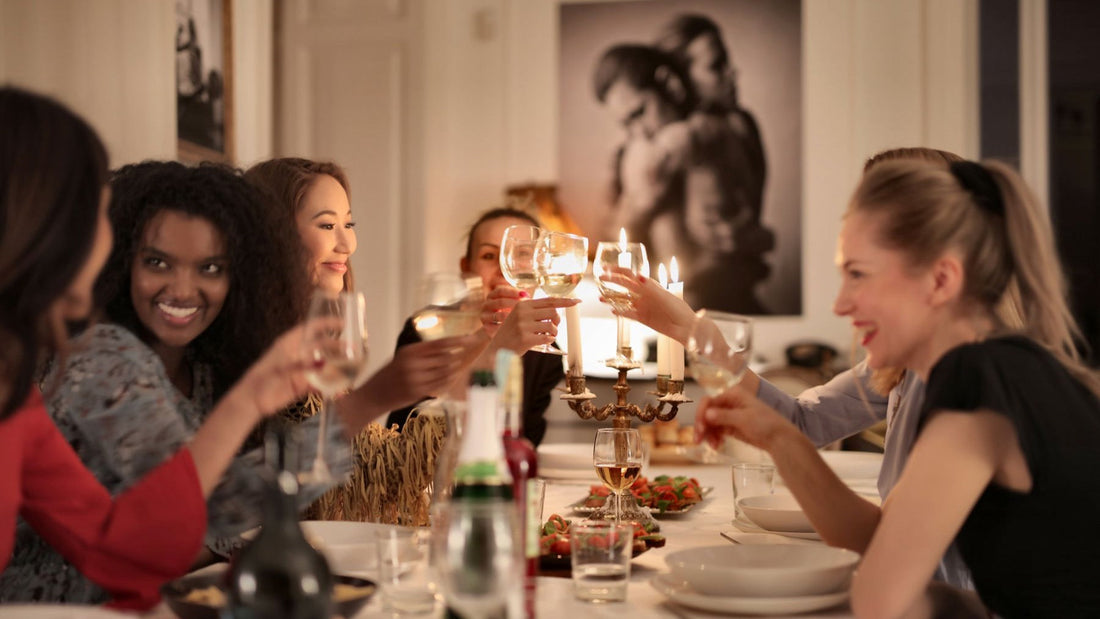 Friends raise wine glasses around a candlelit dinner table during a relaxed evening gathering.