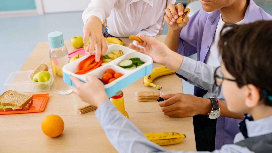 Schoolchildren share fruit, vegetables, sandwiches and snacks from colourful lunch boxes.