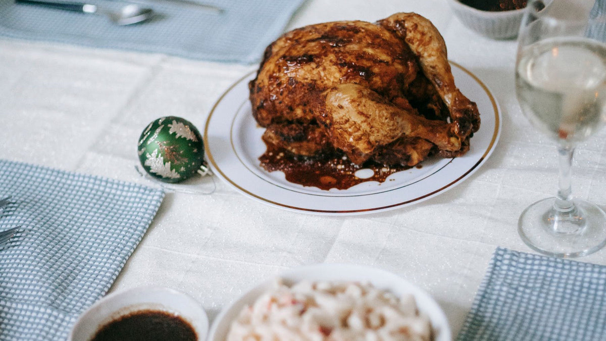 A roasted bird and festive table settings are prepared for a Christmas meal.