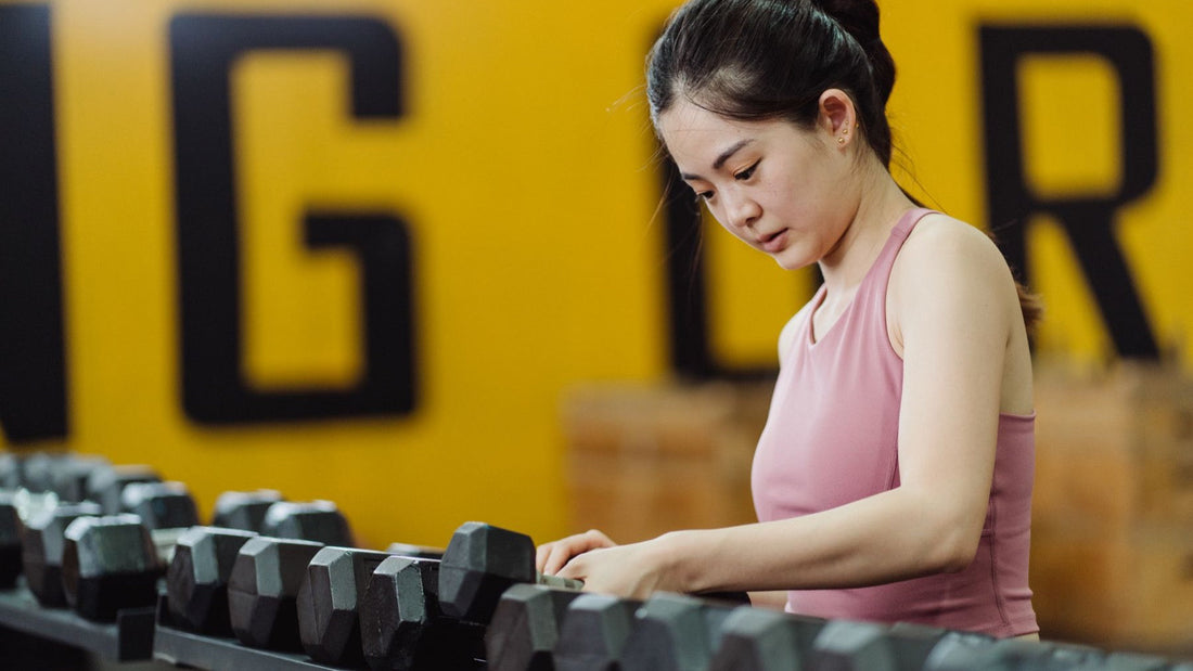 An athlete chooses dumbbells during a focused strength-training session at the gym.