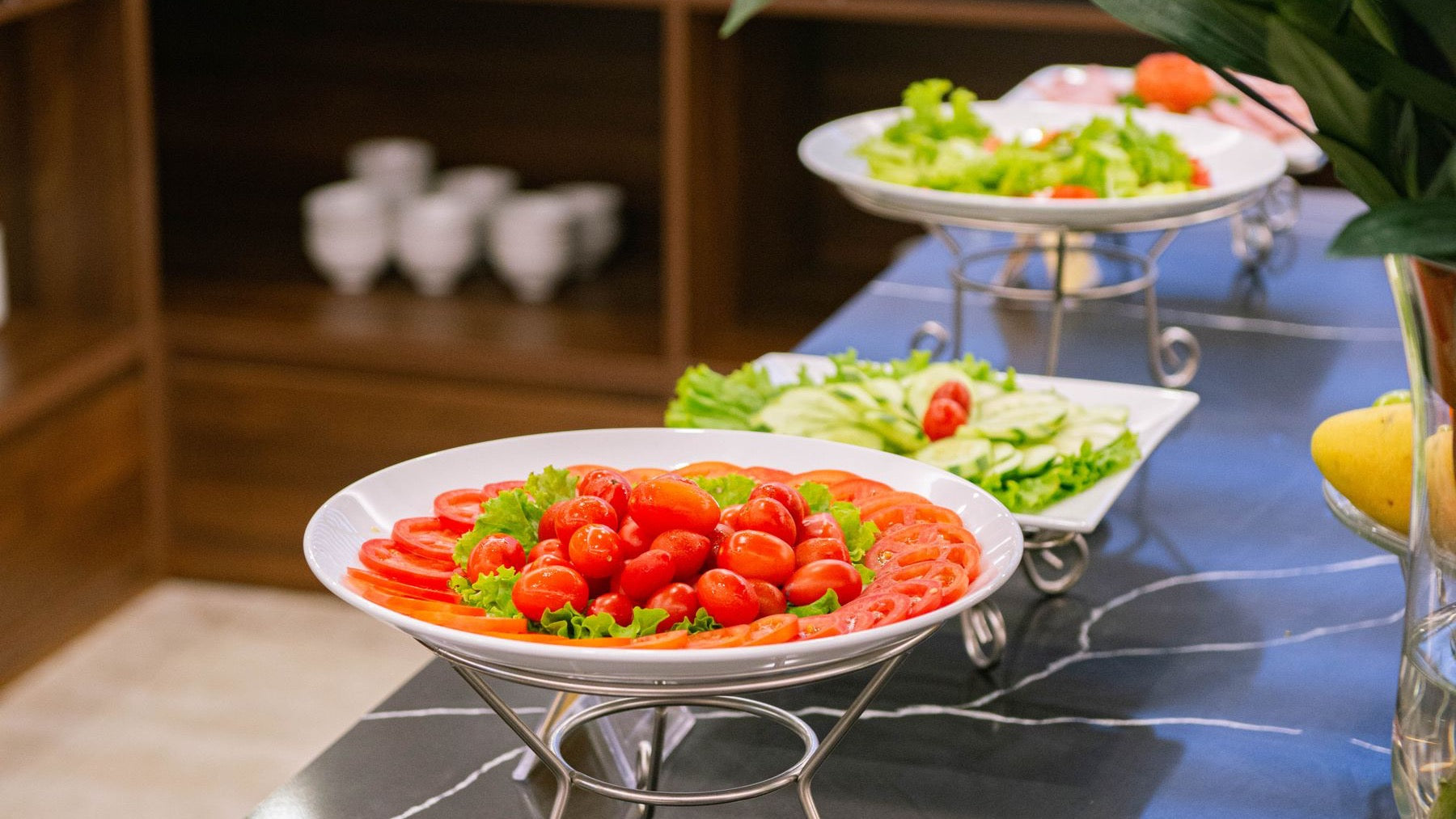 Tomato, cucumber and green salads are arranged across a fresh vegetarian buffet.