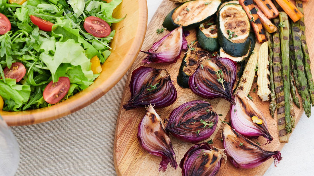 Fresh salad and colourful grilled vegetables are arranged as generous side dishes for a shared meal.