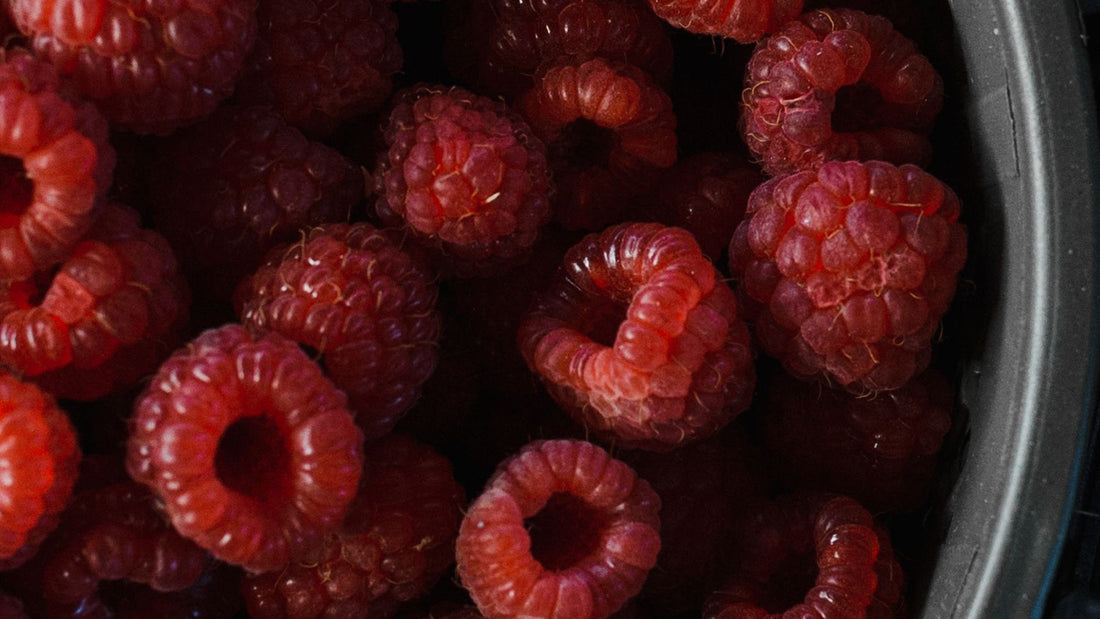 Fresh raspberries fill a dark bowl, reflecting the fruit at the centre of Franui chocolate treats.