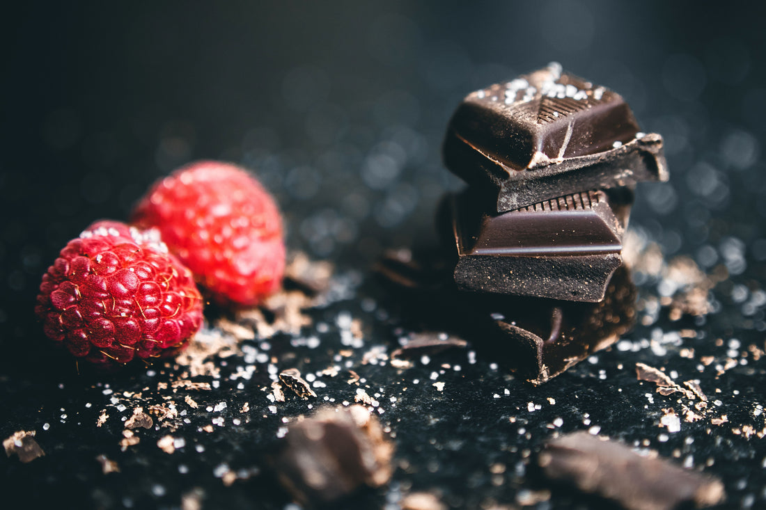 Dark chocolate pieces arranged with fresh raspberries for a party dessert pairing.
