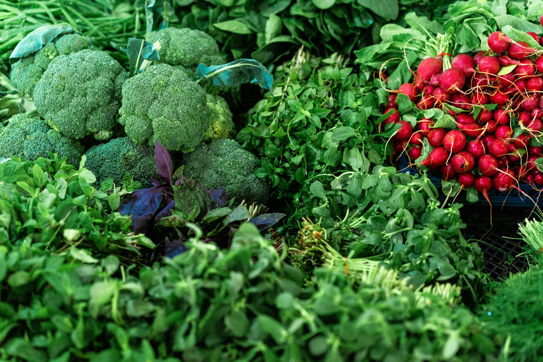 Fresh vegetables including broccoli, spinach, herbs and radishes at a market, representing the plant-based ingredients used in vegan empanadas