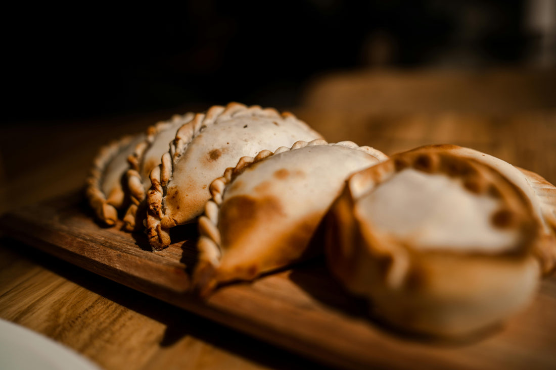 Golden baked Argentinian empanadas with crimped pastry edges served on a rustic wooden board