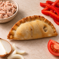 Tunny empanada on light stone with tuna, red capsicum, tomato and onion ingredients